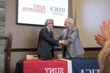 Utica University and SUNY Oneonta Presidents shake hands at the signing of an Articulation Agreement between the two schools on January 24, 2024.