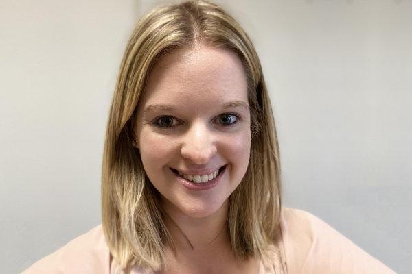 Sara Robinson, a young woman with shoulder-length blond hair, smiles at the camera in front of a beige wall.