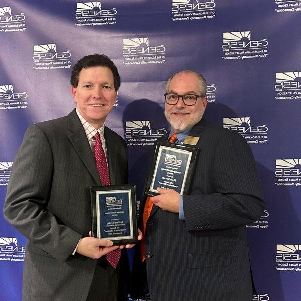 Mark Kovacs and Gary Leising hold up plaques at the Genesis Group's Celebration of 教育 event in November 2023.