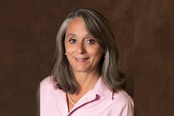 Patricia “Patty” Montone Charvat 'in a pink shirt smiles at the camera.